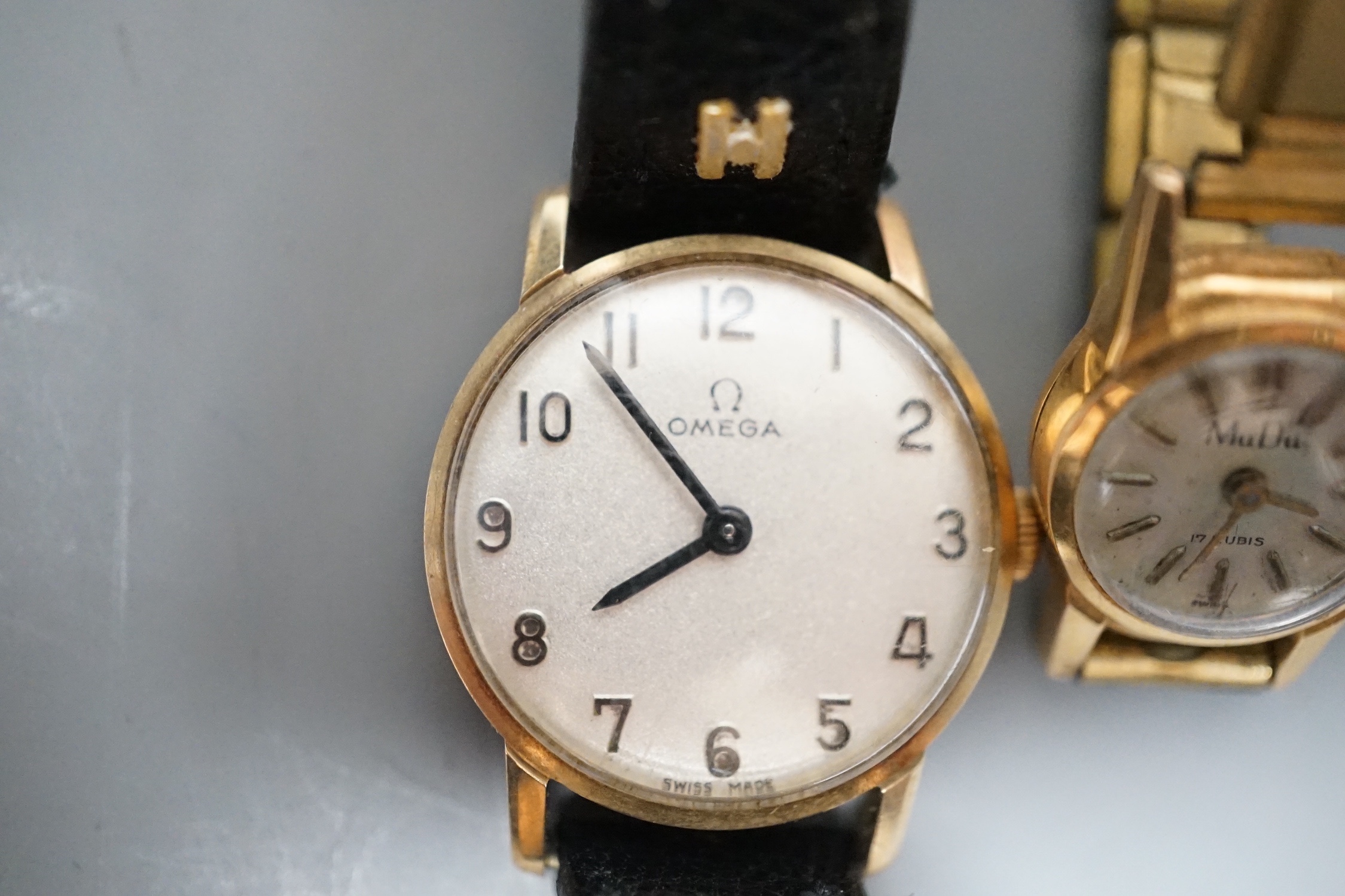 A lady's yellow metal Omega manual wind wrist watch, on a leather strap, with Omega box and a lady's 18k Mudu manual wind wrist watch on gilt metal strap.